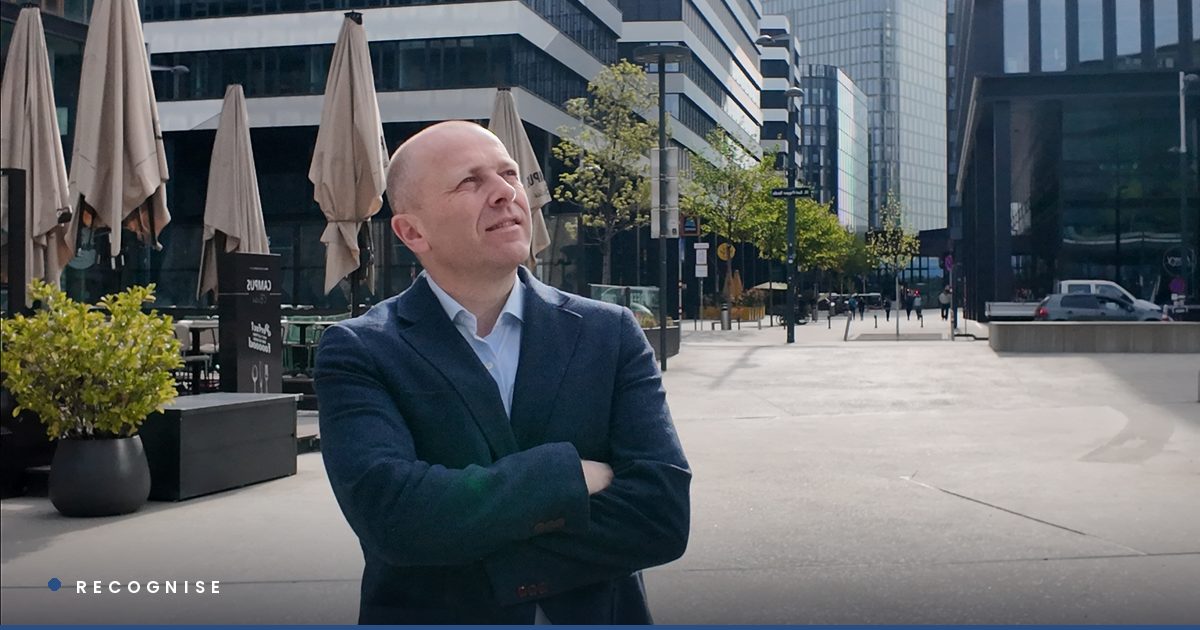 Chris Wilson standing in a corporate district, arms crossed, looking upward