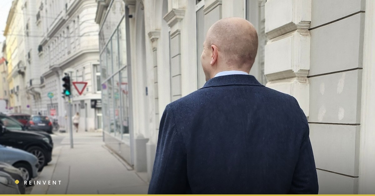 Chris Wilson walking away from the camera down a Vienna street, a green traffic light ahead of him